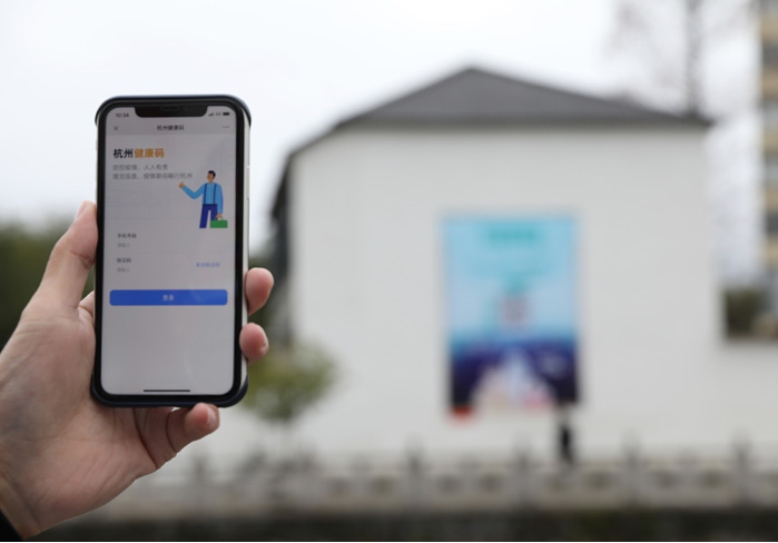 在浙江省杭州市臨安區(qū)天目山鎮(zhèn)，一名居民在“杭州健康碼”海報上掃碼申領(lǐng)個人二維碼。新華社發(fā)